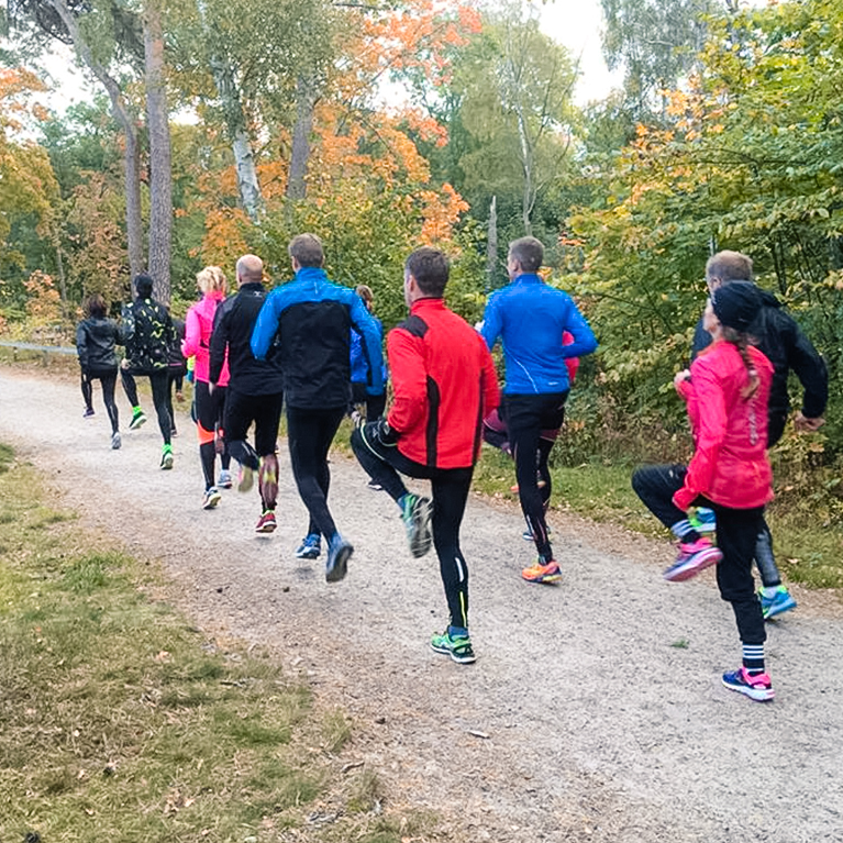 Grupp personer löptränar på grusväg